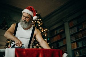 Santa ironing his suit, looks similar to the Santa from the Christmas Chronicles movie. Top 3 Christmas Movies